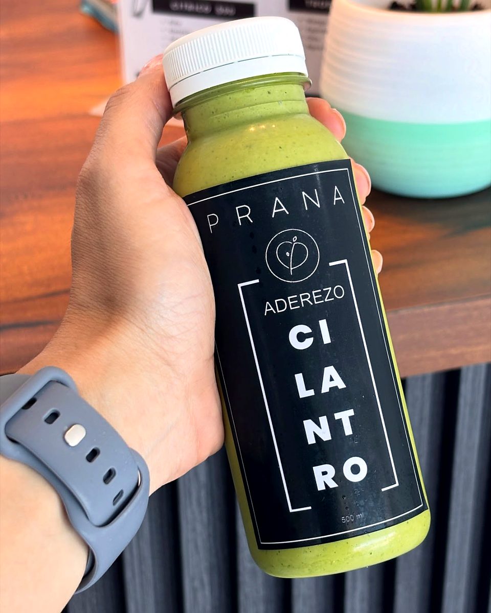 Mano sosteniendo una botella de aderezo de cilantro Prana