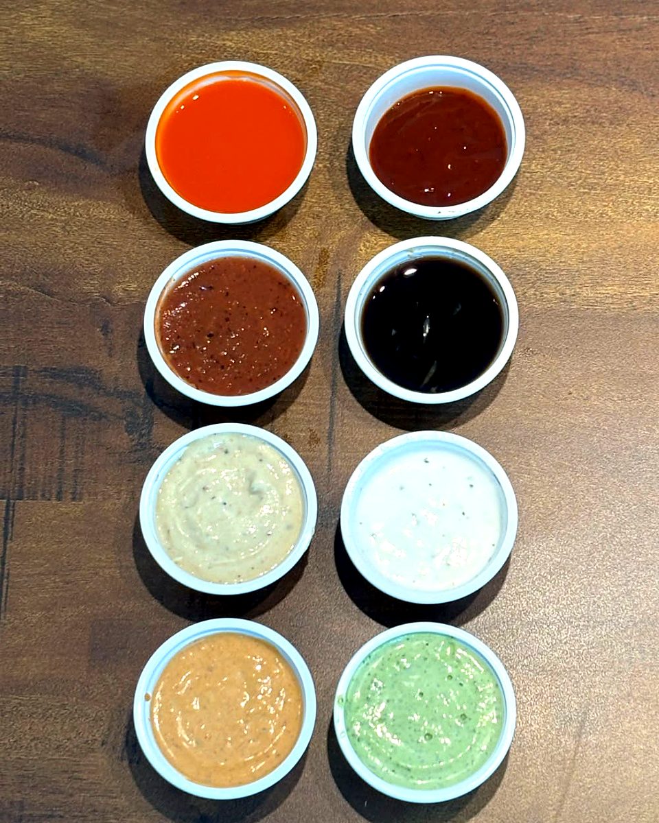 Ocho vasitos con aderezos y salsas de distintos colores y sabores
