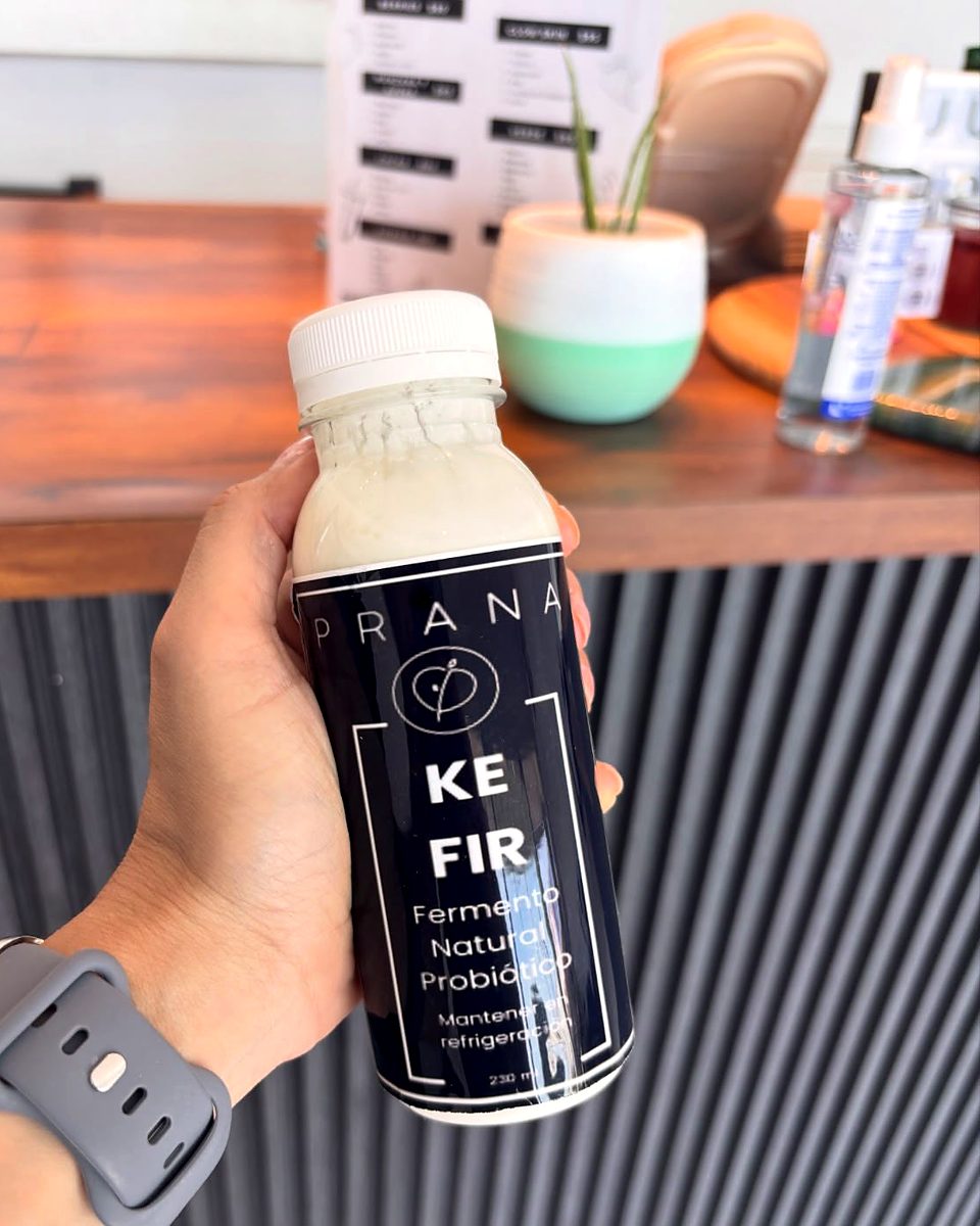 Mano sosteniendo una botella de kéfir Prana de 230 ml