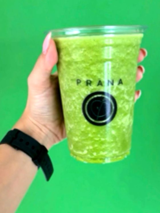 Mano sosteniendo un vaso Prana con smoothie verde